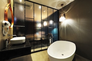 A modern bathroom with a freestanding bathtub, a vanity with a mirror, and a wall-mounted light fixture.