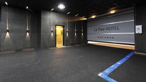 Interior de un hotel con un cartel grande que dice 'La Tree HOTEL', una zona de recepción y un pasillo que conduce a las habitaciones.