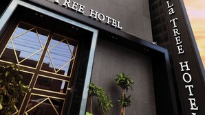 El exterior del Hotel La Tree, con un diseño moderno, ventanas amplias y plantas en macetas.