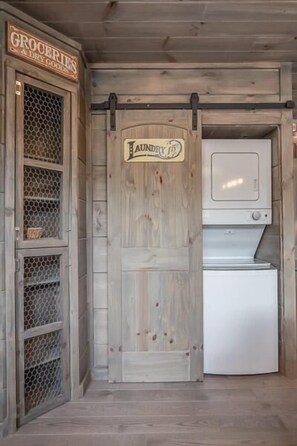A rustic wooden interior with a laundry room, a small refrigerator, and a metal shelving unit. - The Aspen Cabin (Gatlinburg)