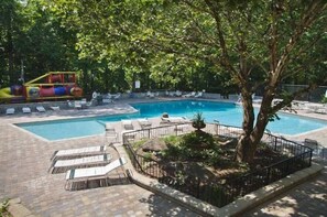 A swimming pool with lounge chairs and a tree. - The Aspen Cabin (Gatlinburg)
