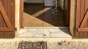 A doorway leading to a kitchen with a refrigerator, microwave, and a bar stool. - 3-star air-con gîte - 5 mins by foot to Monpazier at the heart of the bastides. (Capdrot)