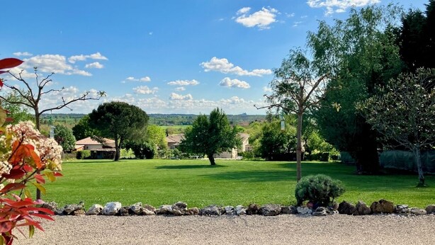 A residential area with a well-maintained lawn, a stone pathway, and a variety of trees. - 3-star air-con gîte - 5 mins by foot to Monpazier at the heart of the bastides. (Capdrot)