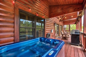 Una cabaña de madera con jacuzzi, mobiliario exterior y una parrilla.