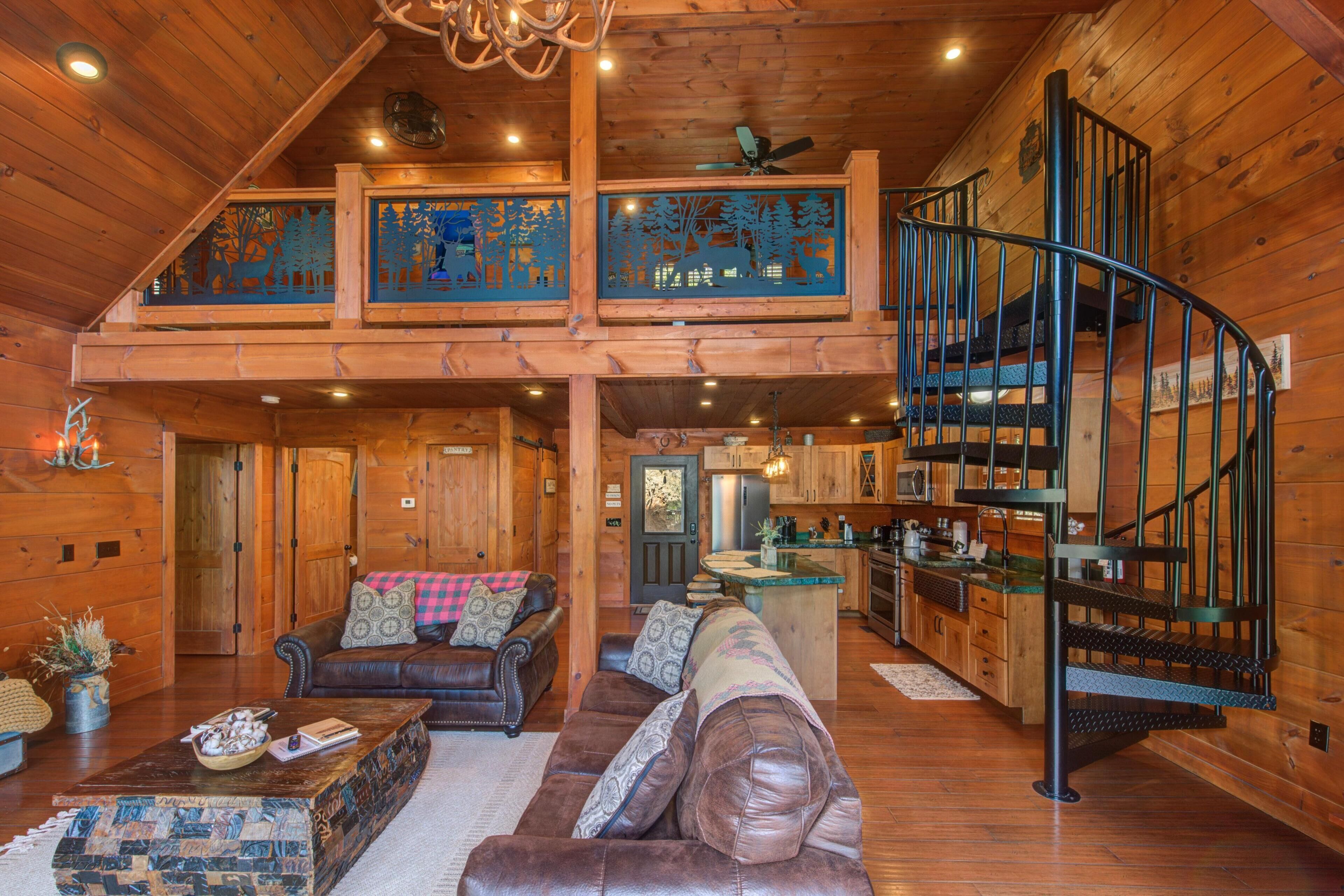 A wooden cabin interior with a living room, a kitchen, and a spiral staircase.