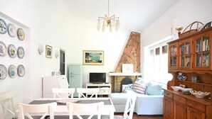Ein Wohnzimmer mit Essbereich, Kamin, Fernseher und Bücherregal.