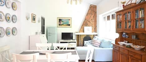 A living room with a dining area, a fireplace, a television, and a bookshelf.