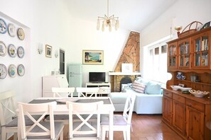 Een woonkamer met een eethoek, een open haard, een televisie en een boekenkast.