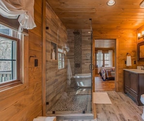 A wooden interior with a shower, a sink, and a mirror. - Black Bear Cabin (Gatlinburg)