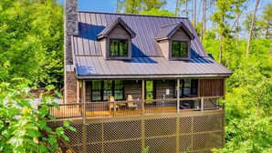 A cabin with a balcony, a chimney, and a view of the surrounding forest. - Black Bear Cabin (Gatlinburg)