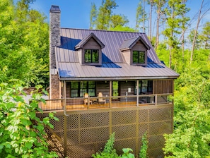 A cabin with a balcony, a chimney, and a view of the surrounding forest. - Black Bear Cabin (Gatlinburg)