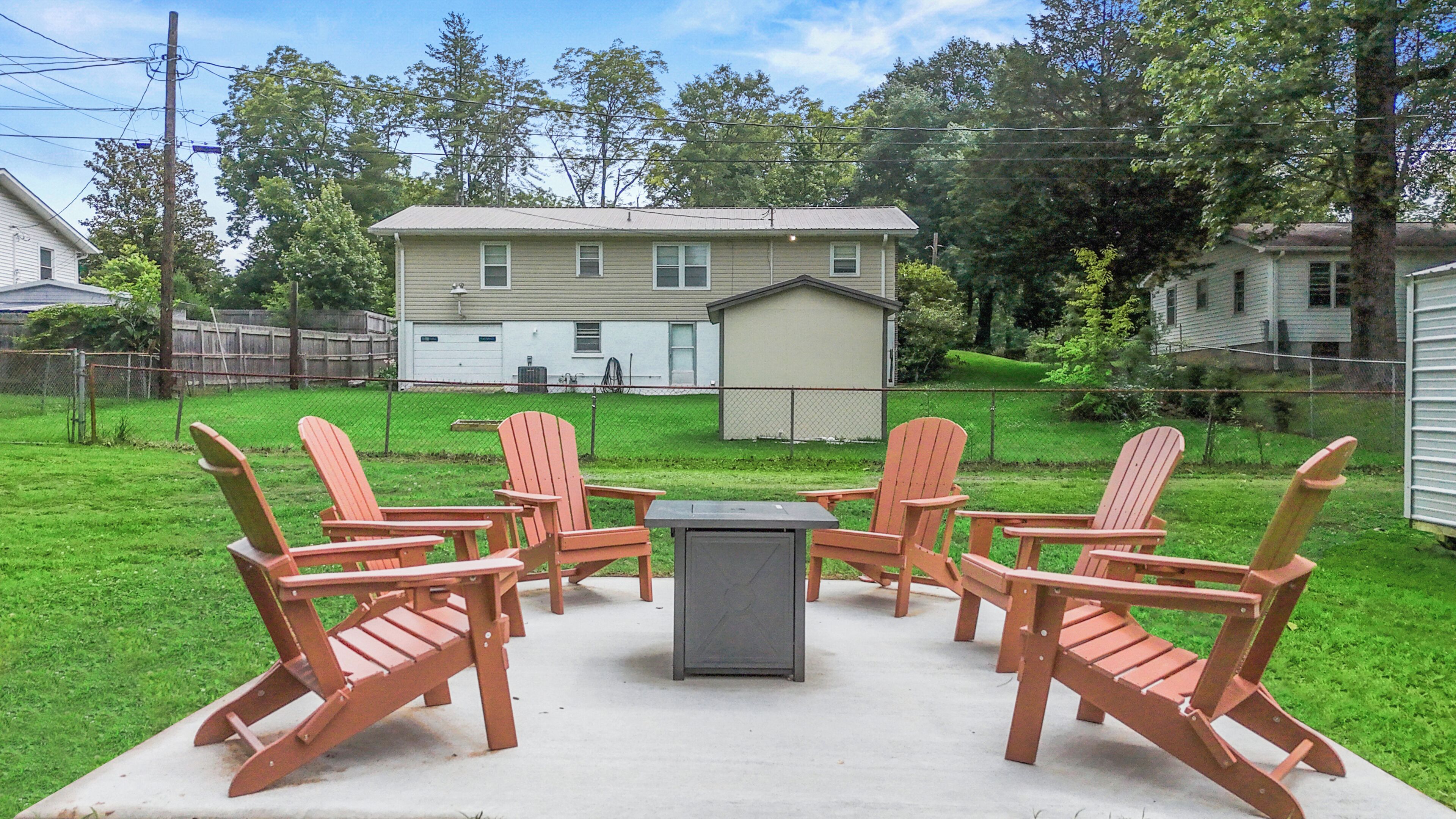 A backyard with a patio set, a house, and a fence.