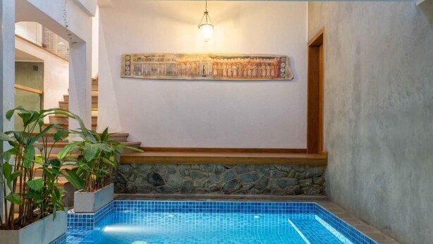 A swimming pool with blue tiles, a stone wall, and a staircase leading to an upper level. - Kings Grove- Kandy (Kandy)