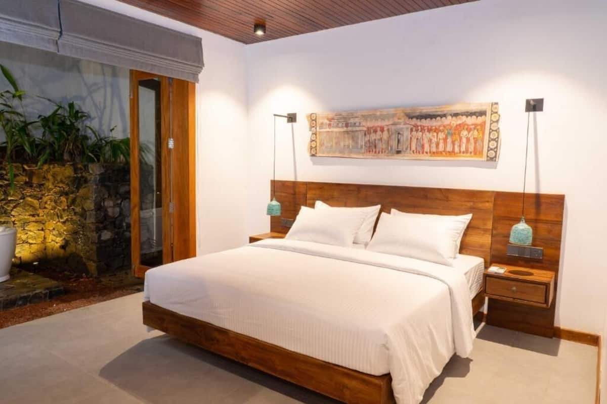 Un dormitorio con cama de madera, pared de piedra y un cuadro en la pared.