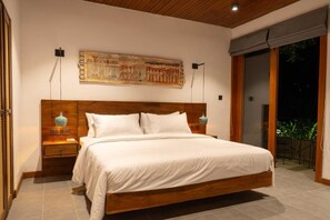 A bedroom with a wooden bed, white bedding, a large painting on the wall, and a view of greenery outside. - Kings Grove- Kandy (Kandy)