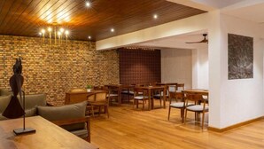 A spacious room with a wooden ceiling, brick wall, and a dining area with wooden furniture. - Kings Grove- Kandy (Kandy)