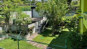 Zona residenziale con una scala in cemento che conduce a un edificio, circondata da vegetazione e da una recinzione.