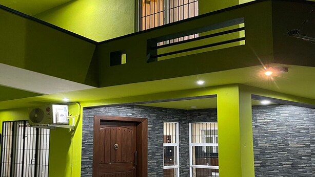 A modern house with a green exterior, a wooden door, and a window with bars. - Cozy 1-bedroom bungalow in quaint Polgasowita with AC (Polgasowita)
