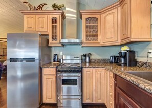 Une cuisine avec des meubles en bois, un réfrigérateur en acier inoxydable, une cuisinière et une machine à café.