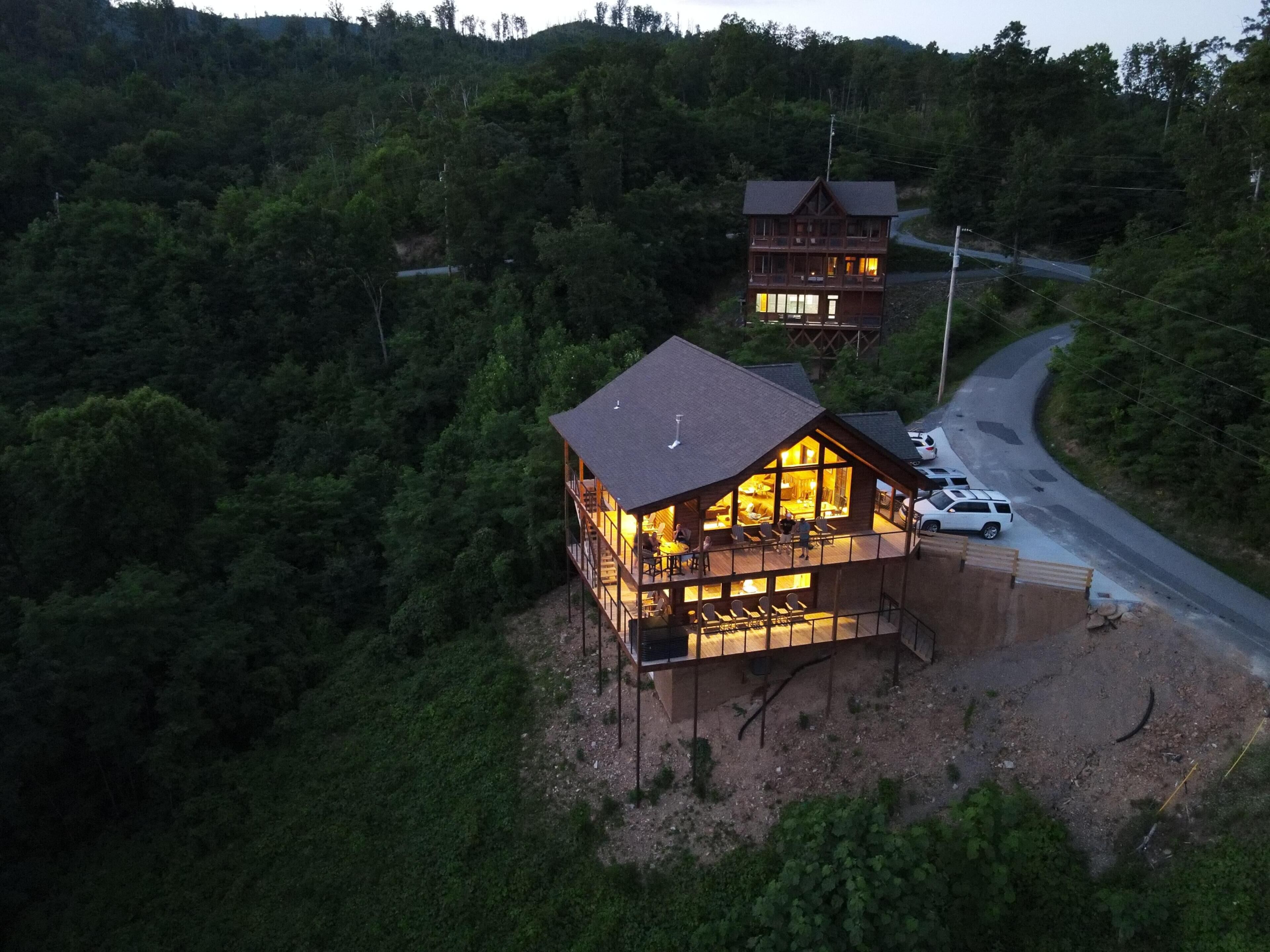 Un chalet à deux étages doté d’un balcon et d’un espace extérieur aménagé, le tout entouré de collines boisées.