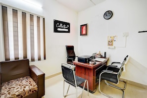 A conference room with a desk, chairs, a clock, and a sign on the wall. - Collection O Kelambakkam Chennai (Tirupporur)