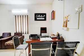 A conference room with a desk, chairs, a printer, a laptop, and a sign on the wall. - Collection O Kelambakkam Chennai (Tirupporur)