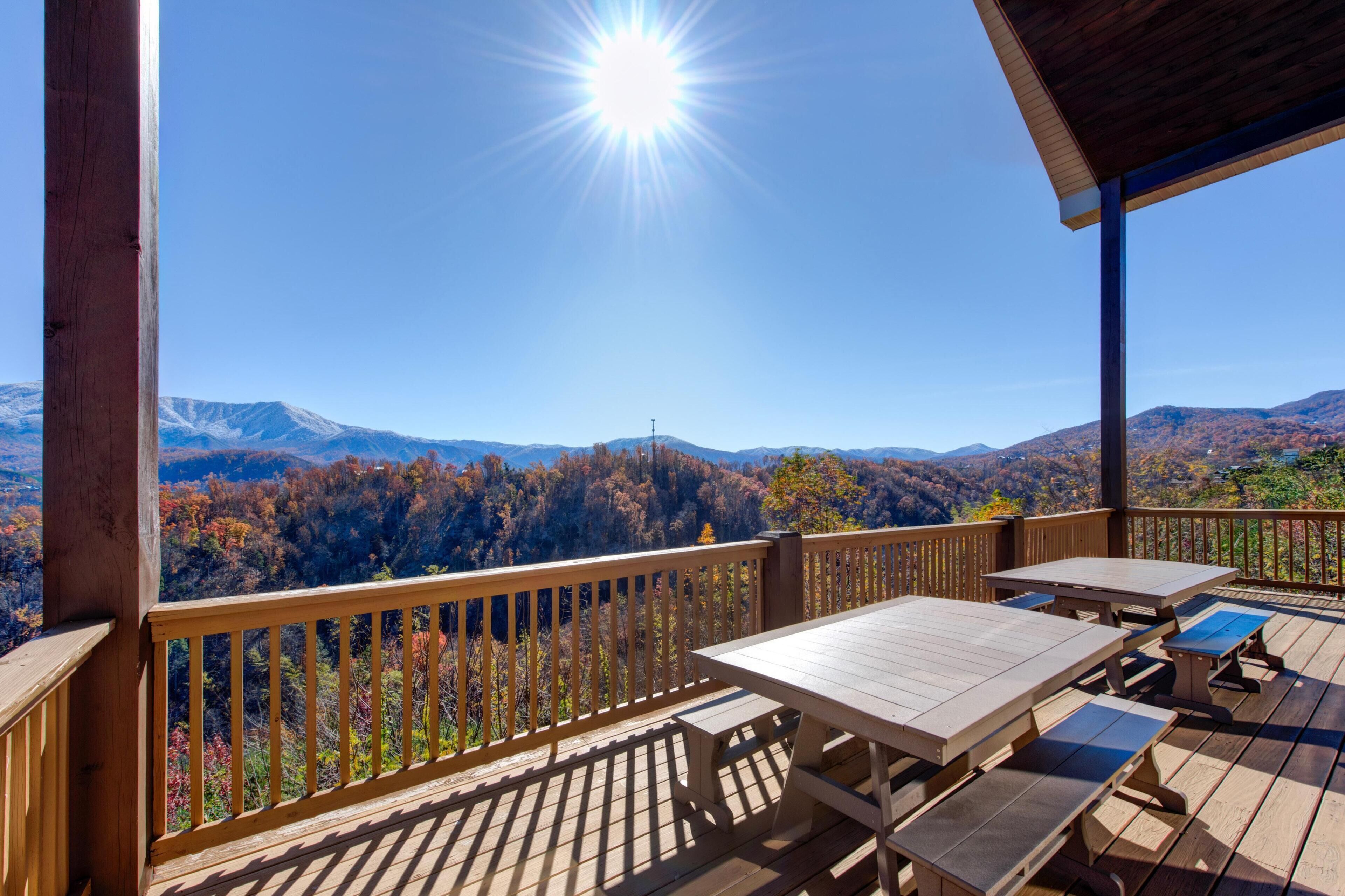 A wooden deck with picnic tables and a view of a mountainous landscape.