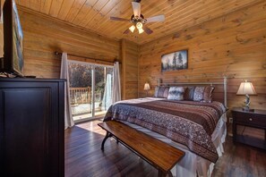 Ein Schlafzimmer einer Holzhütte mit Bett, Bank, Deckenventilator und einem Gemälde an der Wand.