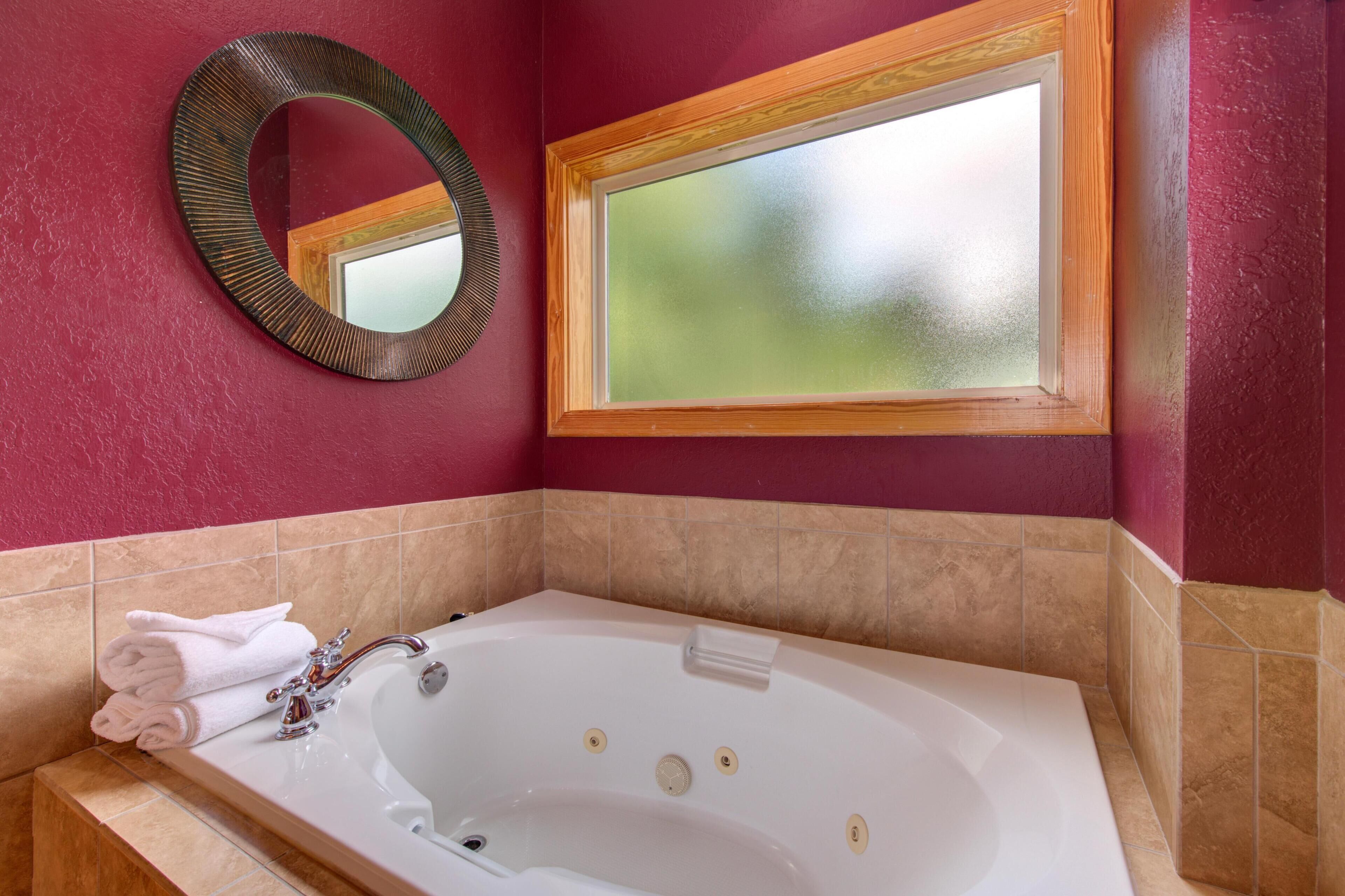Un baño con bañera, espejo y ventana.