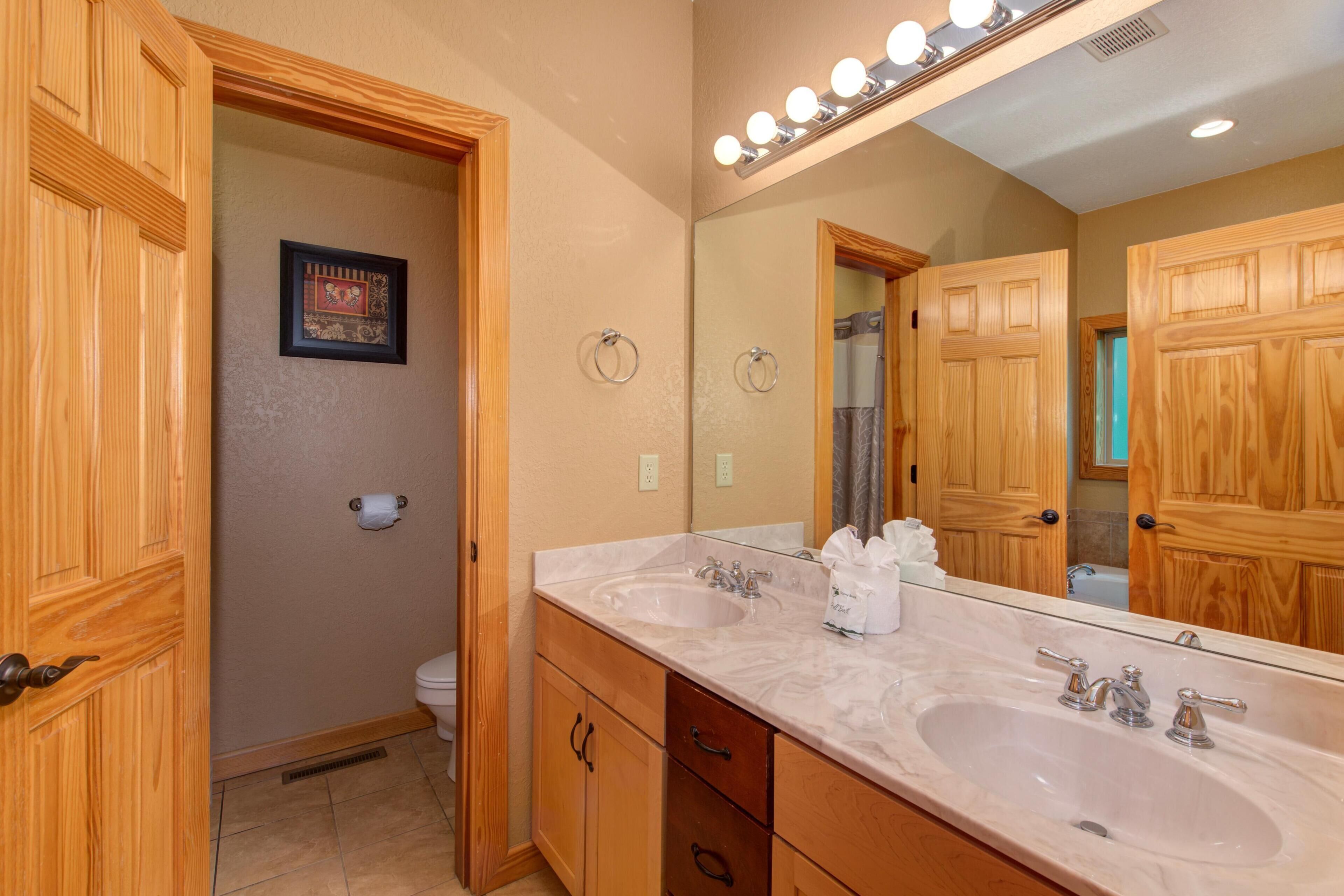 Un bagno con mobili in legno, un doppio lavabo, uno specchio grande e un quadro incorniciato appeso al muro.