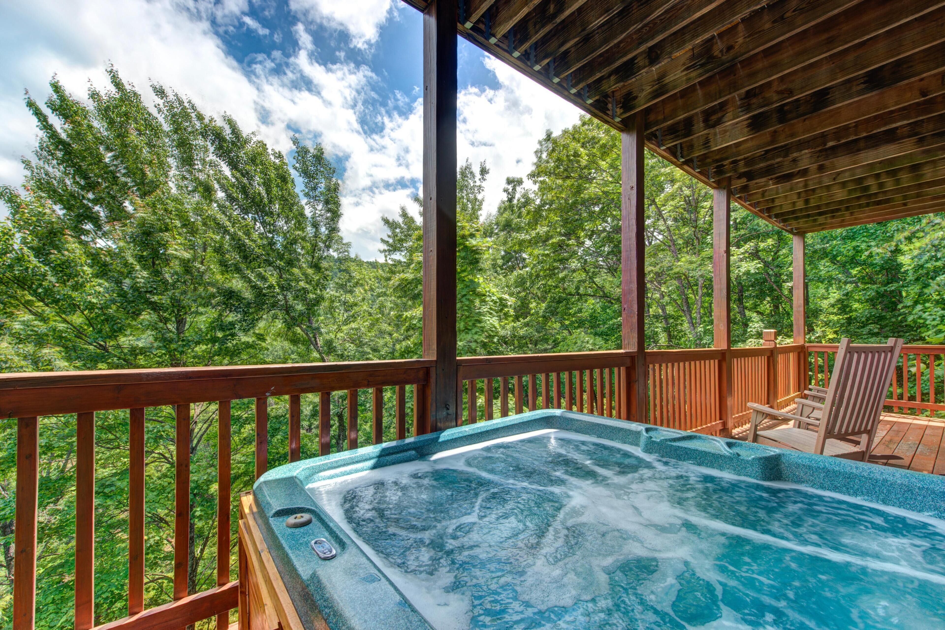 A hot tub on a wooden deck with a view of a forest.