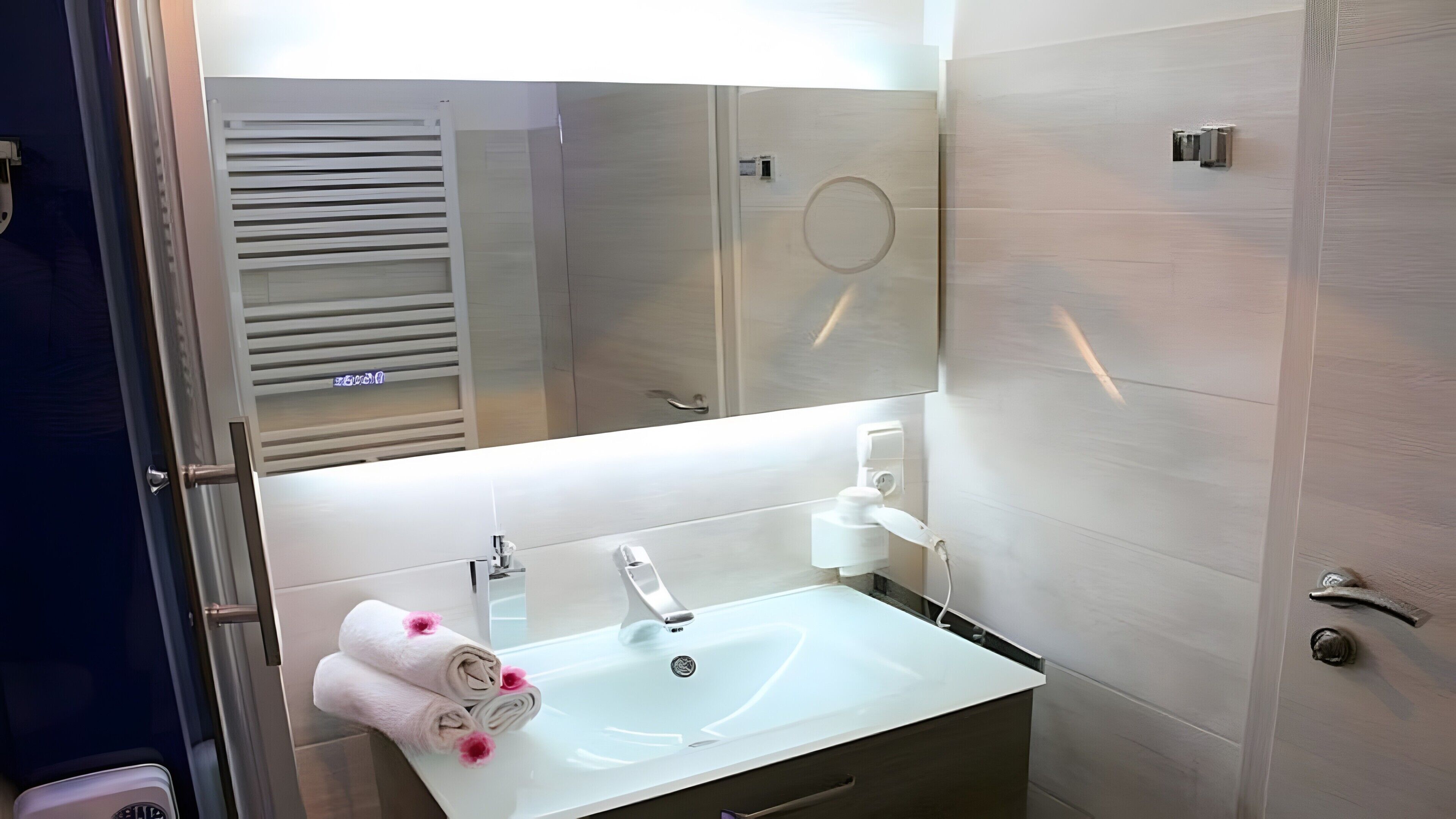 Ein Badezimmer mit einem weißen Waschbecken, einem Spiegel und einem Handtuchhalter mit Handtüchern.