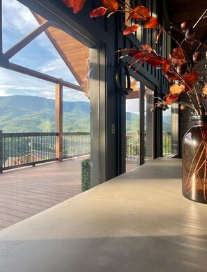 Ein Balkon mit Blick auf Berge, eine Vase mit getrockneten Ästen und ein Holellentgel.