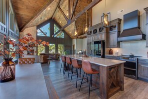 A spacious kitchen with a large island, wooden beams, and modern appliances. - The Ember (Gatlinburg)