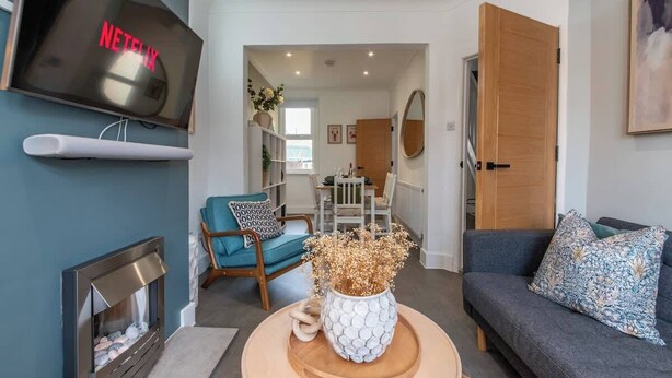 Ein Wohnzimmer mit Flachbildfernseher, Kamin, Sofa und Essbereich im Hintergrund.