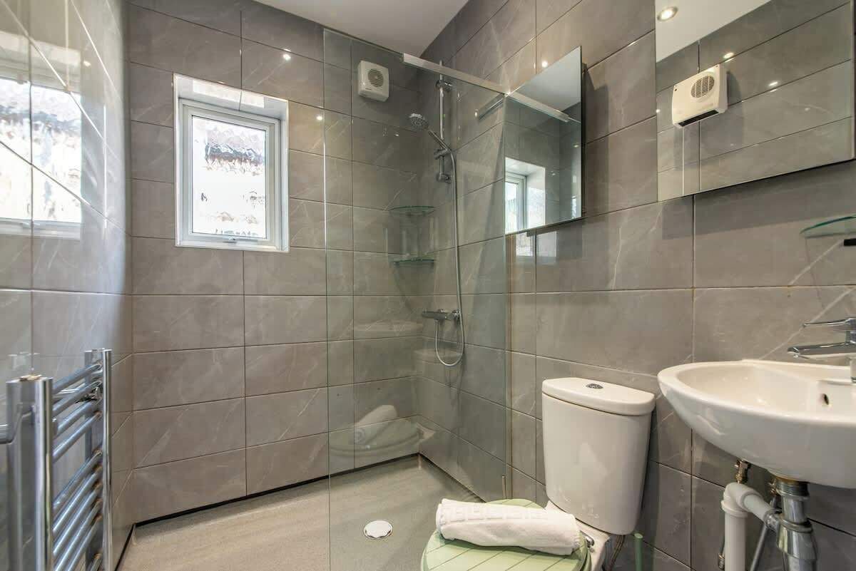 Un bany modern amb plat de dutxa envoltat de vidre, vàter i rentapèns.