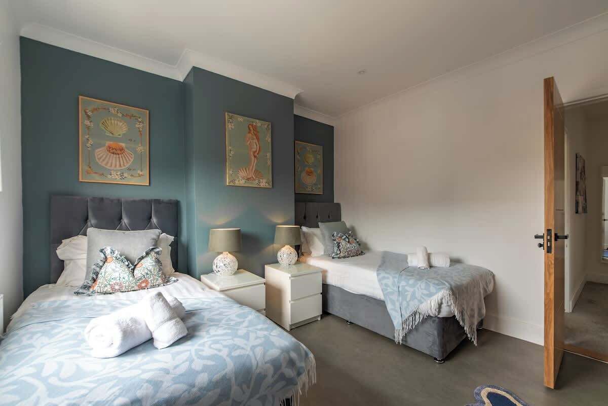 Un dormitorio con dos camas, mesitas de noche y decoración en la pared.