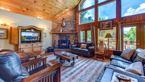 Una sala de estar acogedora con chimenea, muebles de cuero y ventanas amplias.