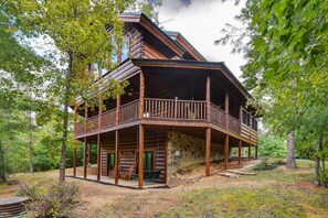 A log cabin with a balcony, surrounded by trees. - One More Night (Sevierville)