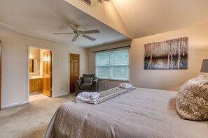 A bedroom with a bed, a ceiling fan, a window with blinds, a painting, and a chair. - Palmer's Place (Sevierville)
