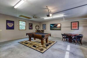 Ein Zimmer mit Billardtisch, einem Esstisch mit Stühlen und verschiedenen gerahmten Kunstwerken an den Wänden.
