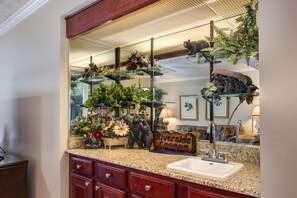 A bathroom with a granite countertop, a sink, a mirror, and a sign that reads 'Riverside Escape'. - Riverside Escape (Gatlinburg)