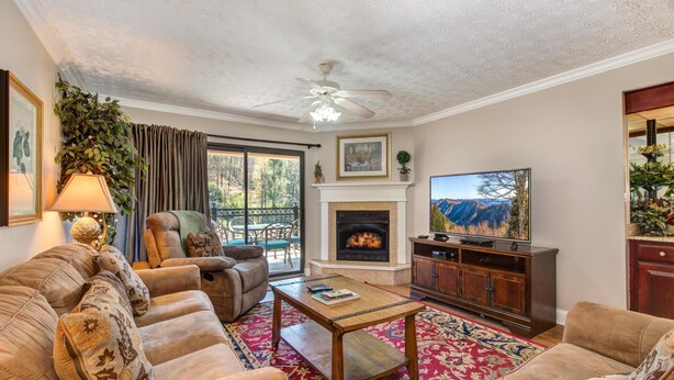A living room with a fireplace, sofa, television, and a ceiling fan. - Riverside Escape (Gatlinburg)