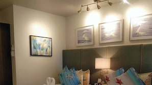 Ein Hotelzimmer mit zwei Betten, einem Nachttisch, einer Lampe und Bildern an den Wänden.