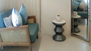 Ein modernes Wohnzimmer mit einer Couch, einem runden Beistelltisch, einem Sessel und einem großen Spiegel.