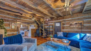 A log cabin interior with a living room, kitchen, and staircase. - Cricket Hollow Lodge (Cosby)