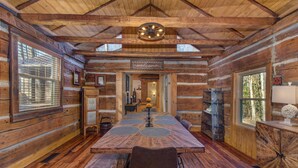 A log cabin interior with a wooden dining table, chairs, a chandelier, and a 'welcome' sign. - Cricket Hollow Lodge (Cosby)
