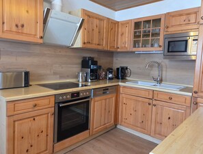 A kitchen with wooden cabinets, a built-in oven, a microwave, a toaster, and a coffee maker.