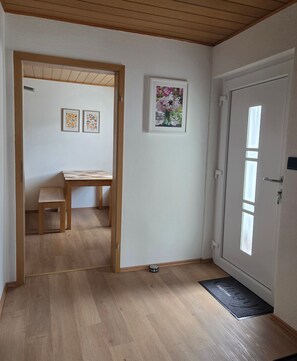 A hallway with a wooden door, a bench, and framed pictures on the wall.