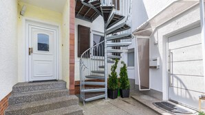 Un immeuble résidentiel doté d’un escalier en colimaçon menant à un palier du deuxième étage, d’une porte blanche et d’une porte de garage.